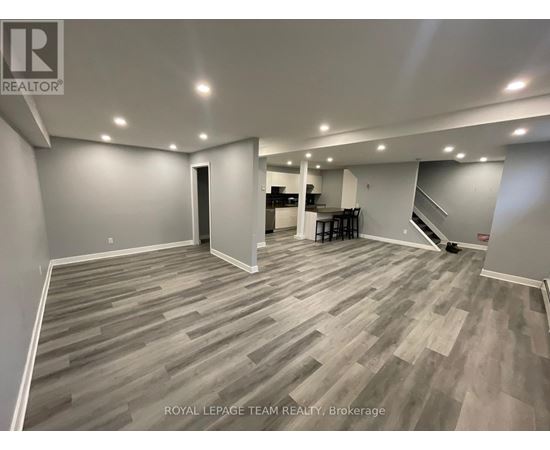 A spacious room with wooden flooring and a bar area in the corner.