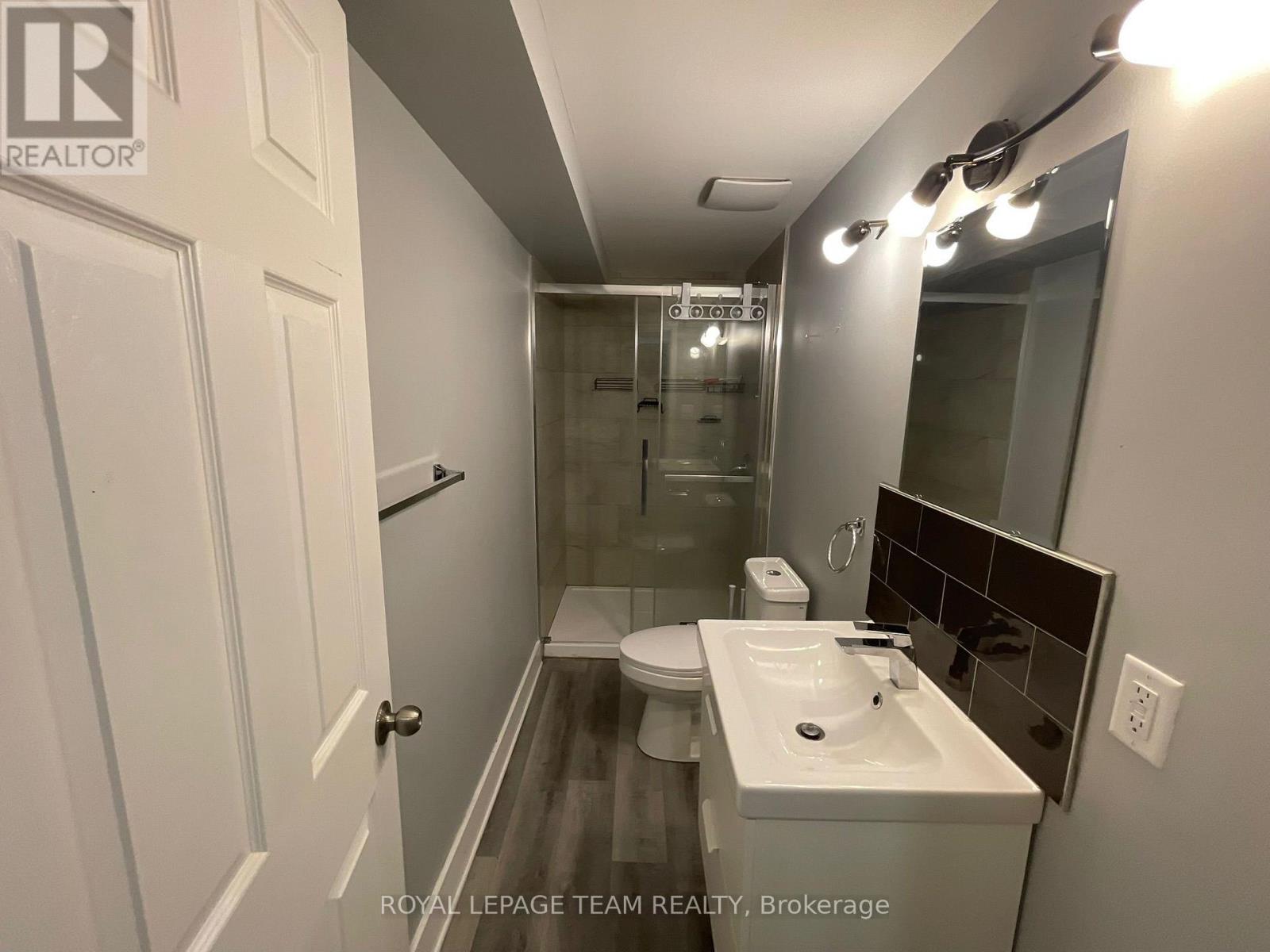 A bathroom with a toilet, sink, and mirror.