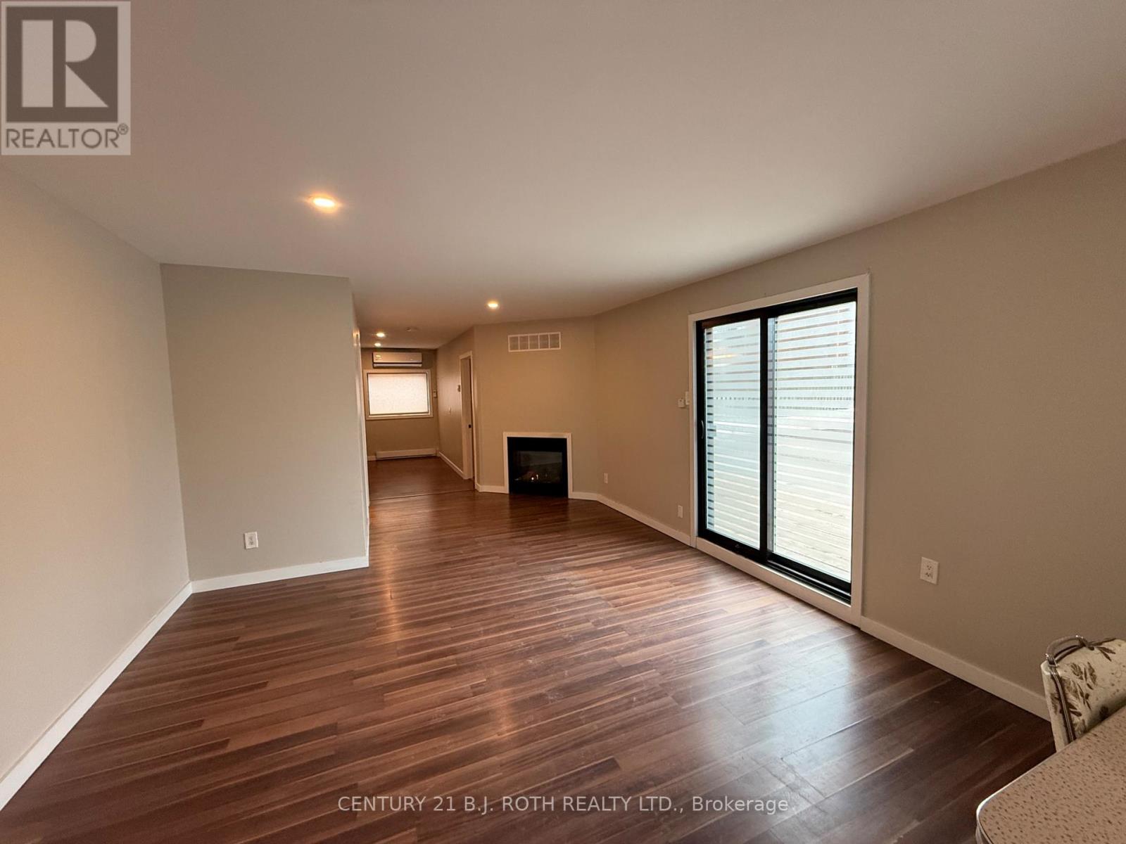 A spacious room with wooden flooring and a fireplace.