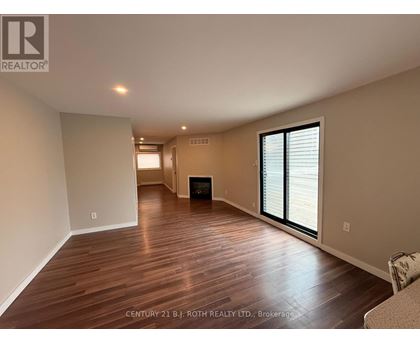 A spacious room with wooden flooring and a fireplace.