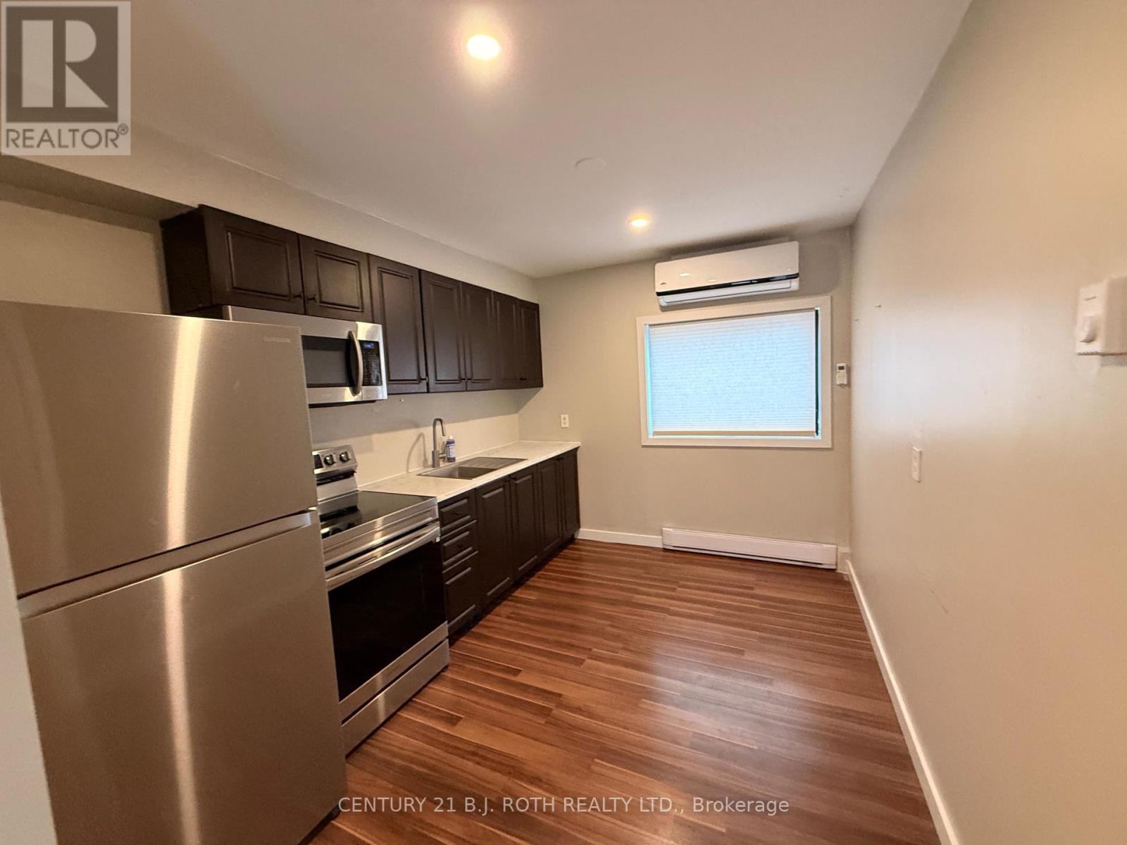 A kitchen with stainless steel appliances and wooden floors.