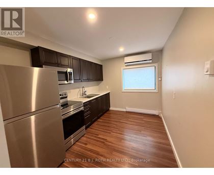 A kitchen with stainless steel appliances and wooden floors.