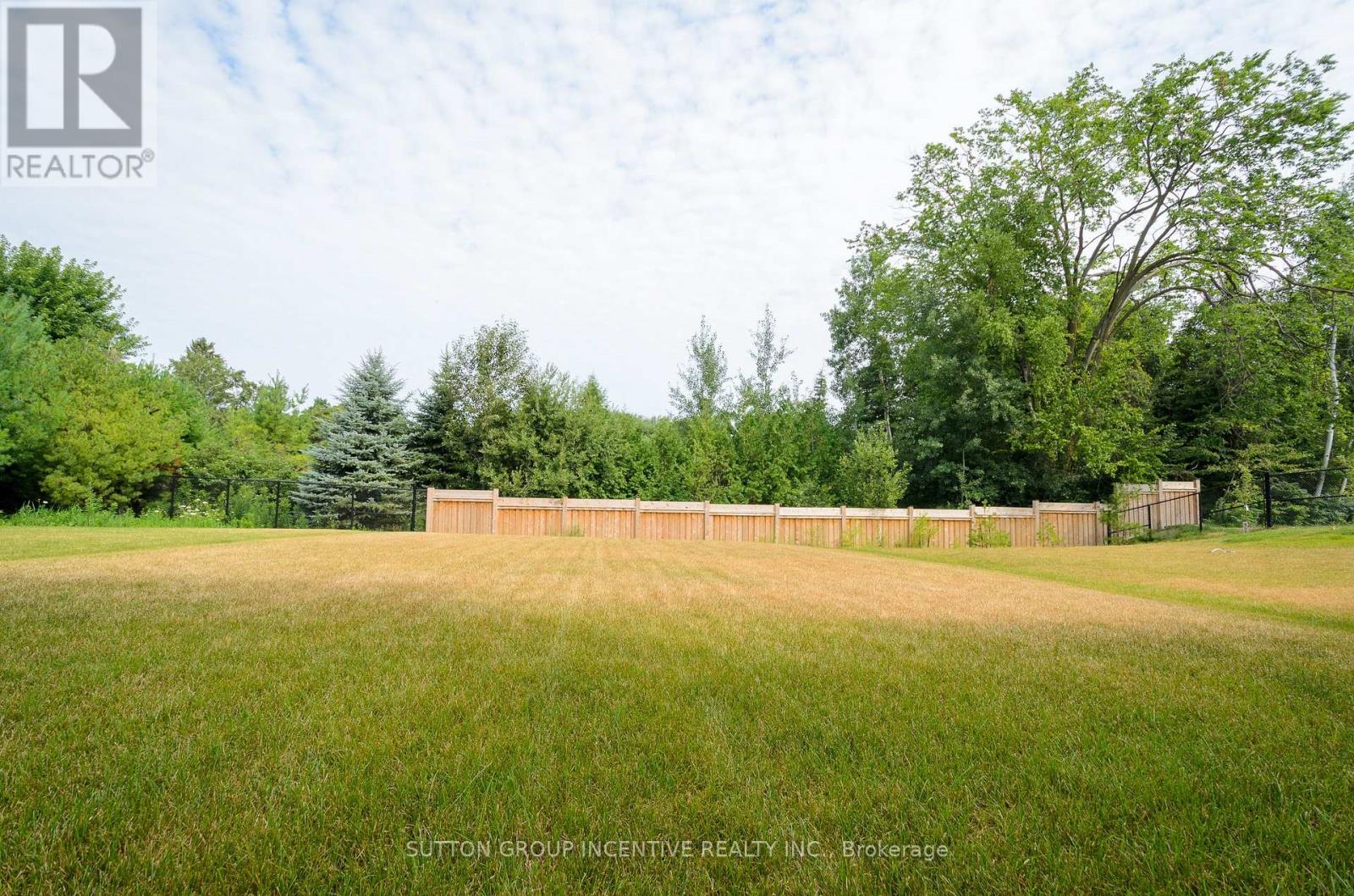 A field with a fence and trees in the background.