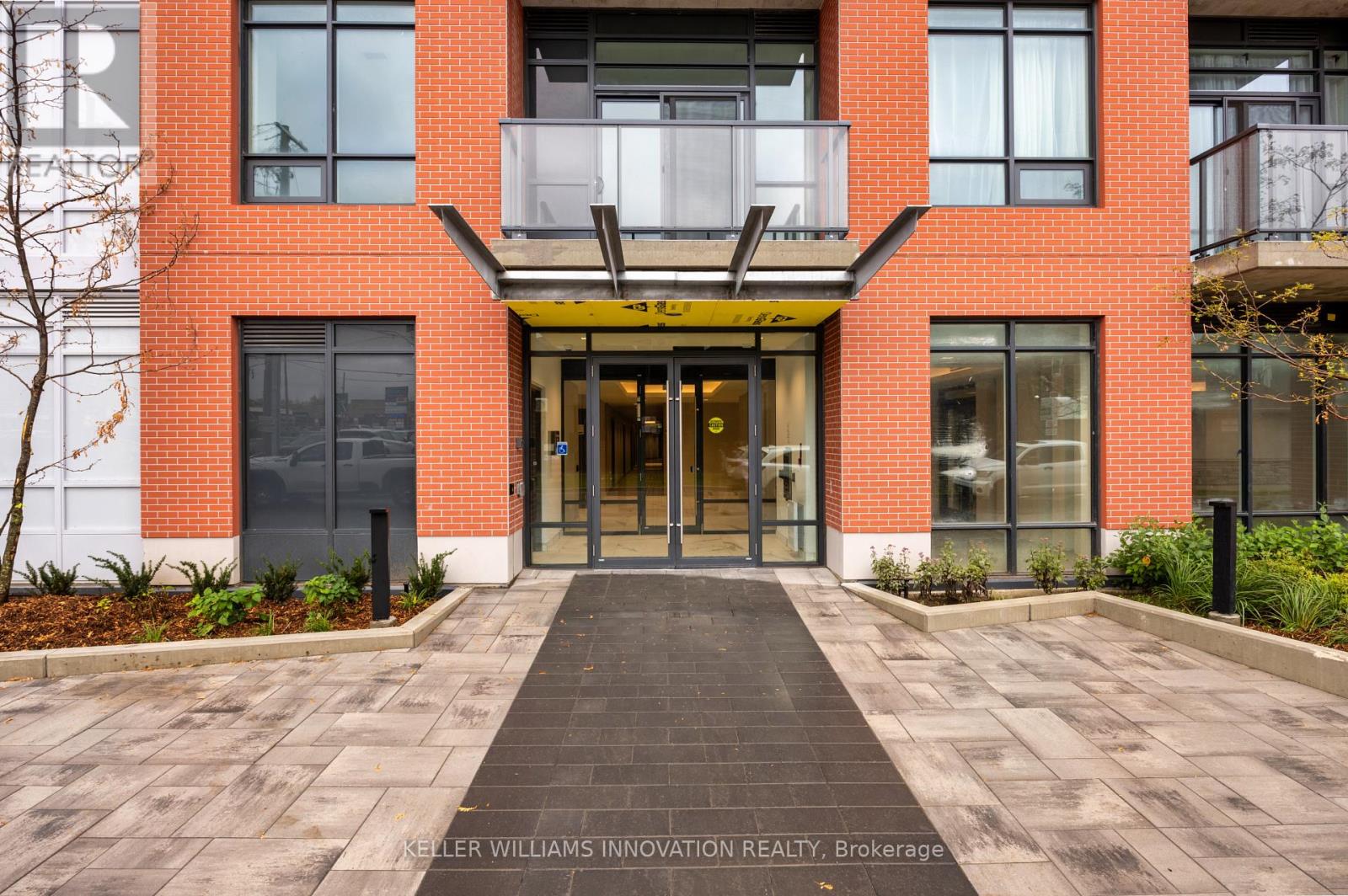 A red brick building with a glass entrance and a yellow awning.