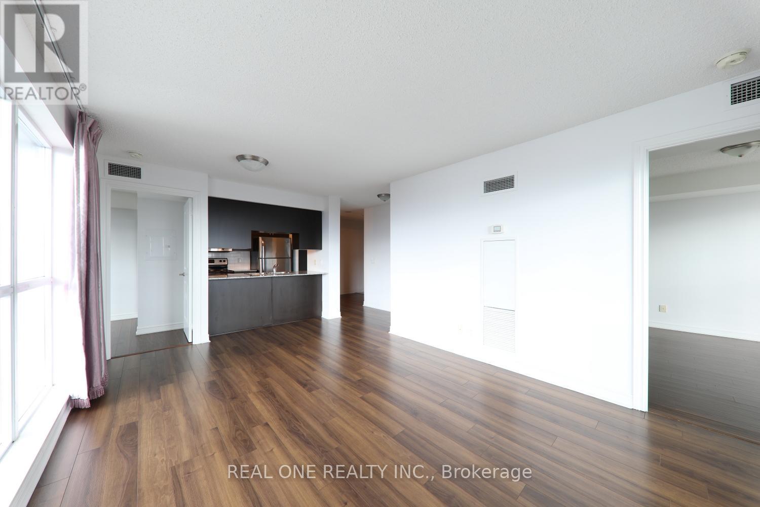 A spacious room with wooden flooring and white walls.