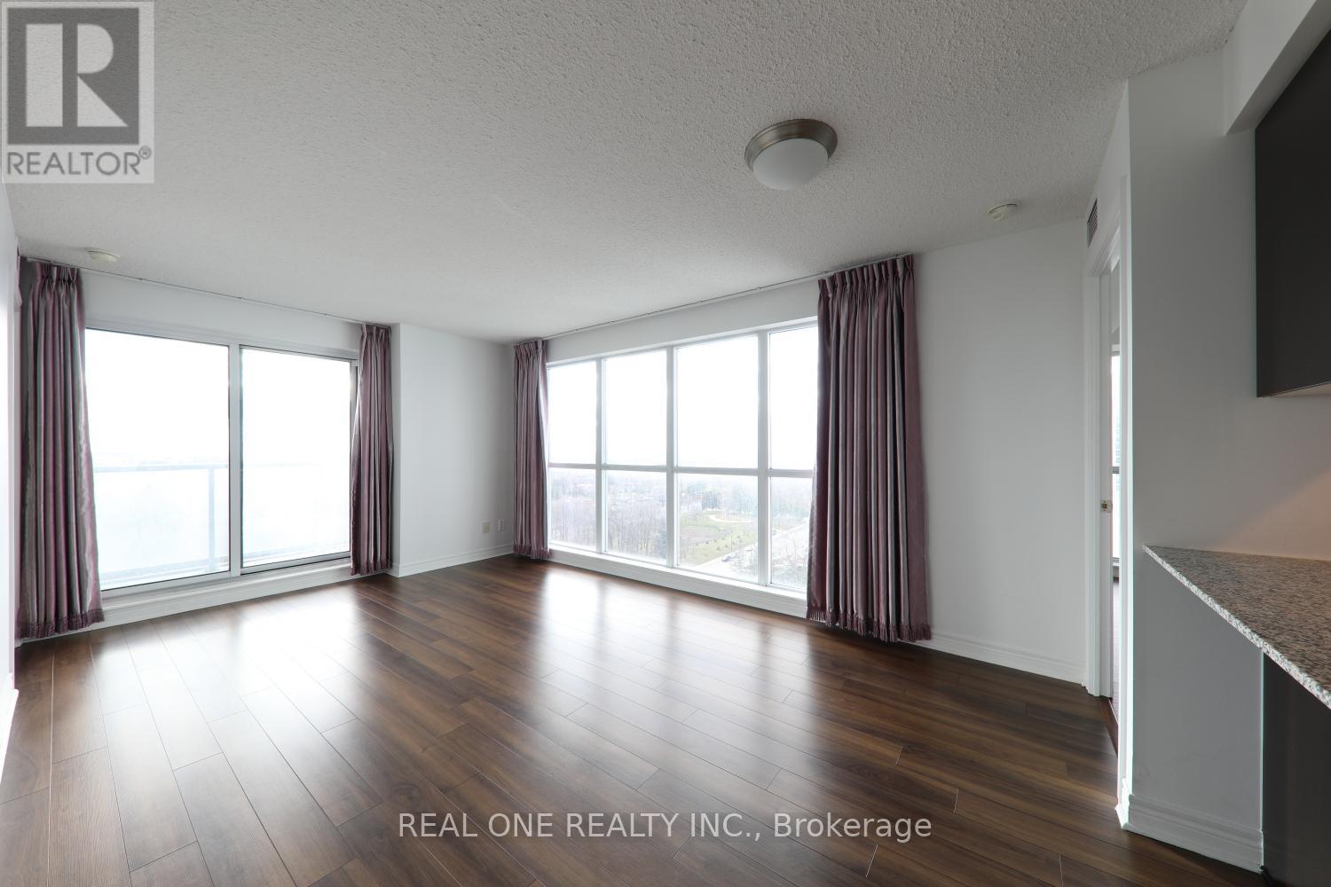 A room with wooden floors and large windows with curtains.