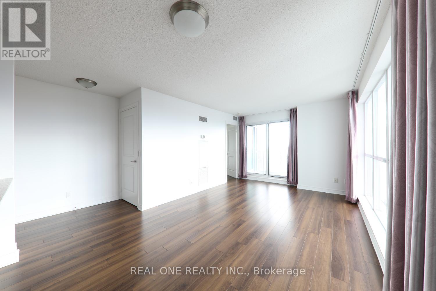 A spacious room with wooden floors and white walls.