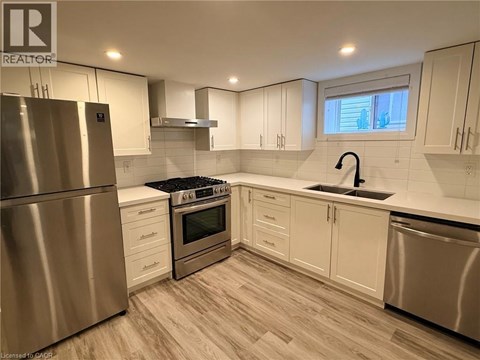 A modern kitchen with a stainless steel refrigerator and wooden flooring.