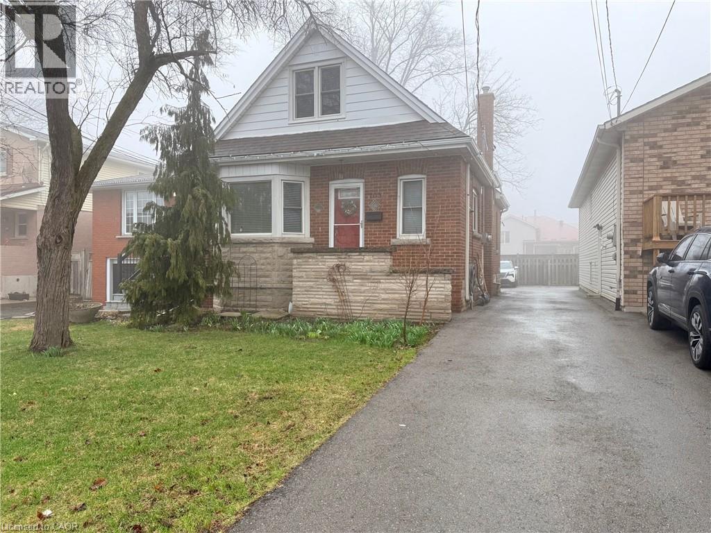 A residential street with a house on the left and a car parked on the right.