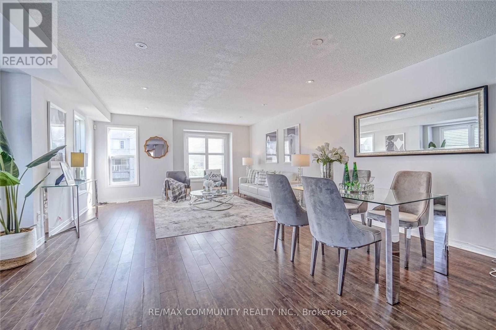A dining room with a glass table and grey chairs.