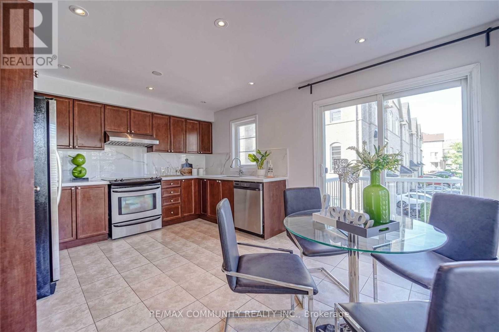 A modern kitchen with a glass table and grey chairs.
