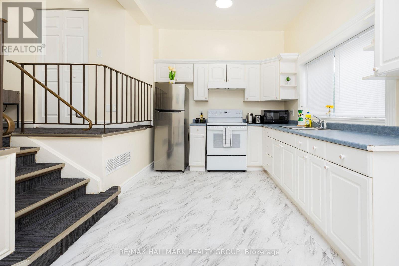 A kitchen with white cabinets and a marble floor.
