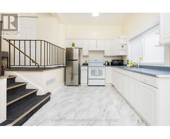 A kitchen with white cabinets and a marble floor.