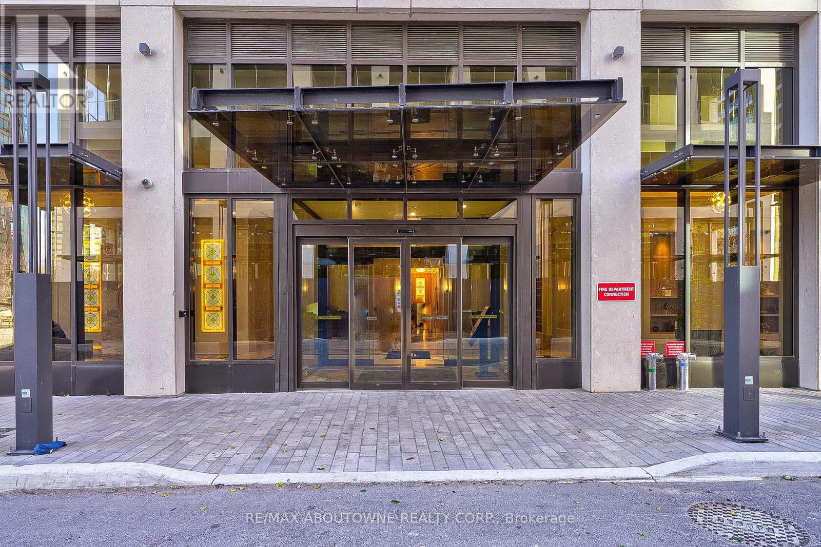 The entrance to a building with a glass canopy and a red sign that reads "RE/MAX ABOUTOWNE REALTY CORP. Brokerage".