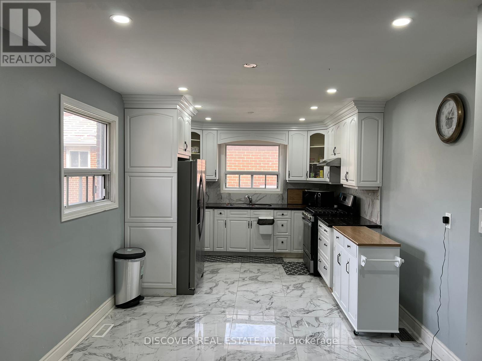 A kitchen with white cabinets and a marble floor.