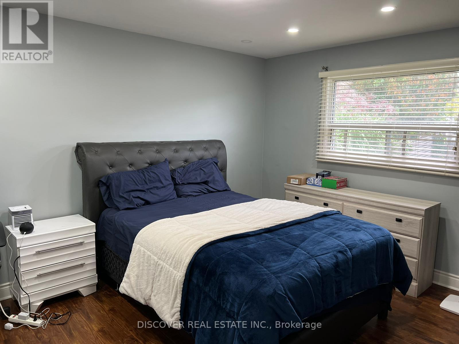A bedroom with a bed, nightstand, and window.