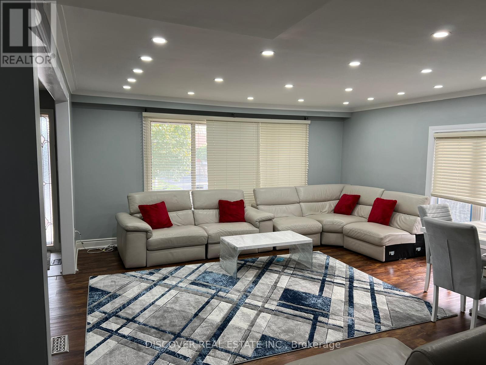 A living room with a large sectional sofa and a rug.