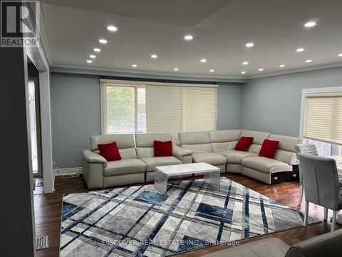 A living room with a large sectional sofa and a rug.