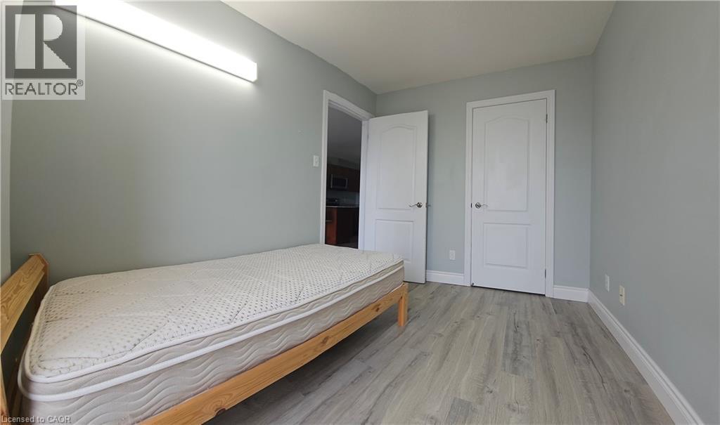 A bedroom with a bed, two doors, and a light on the wall.