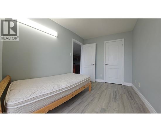 A bedroom with a bed, two doors, and a light on the wall.