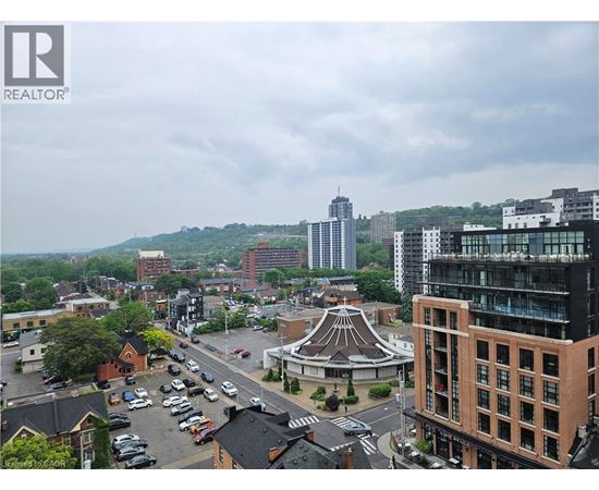 A cityscape with a mix of modern and older buildings, a parking lot, and a gazebo-like structure in the center.