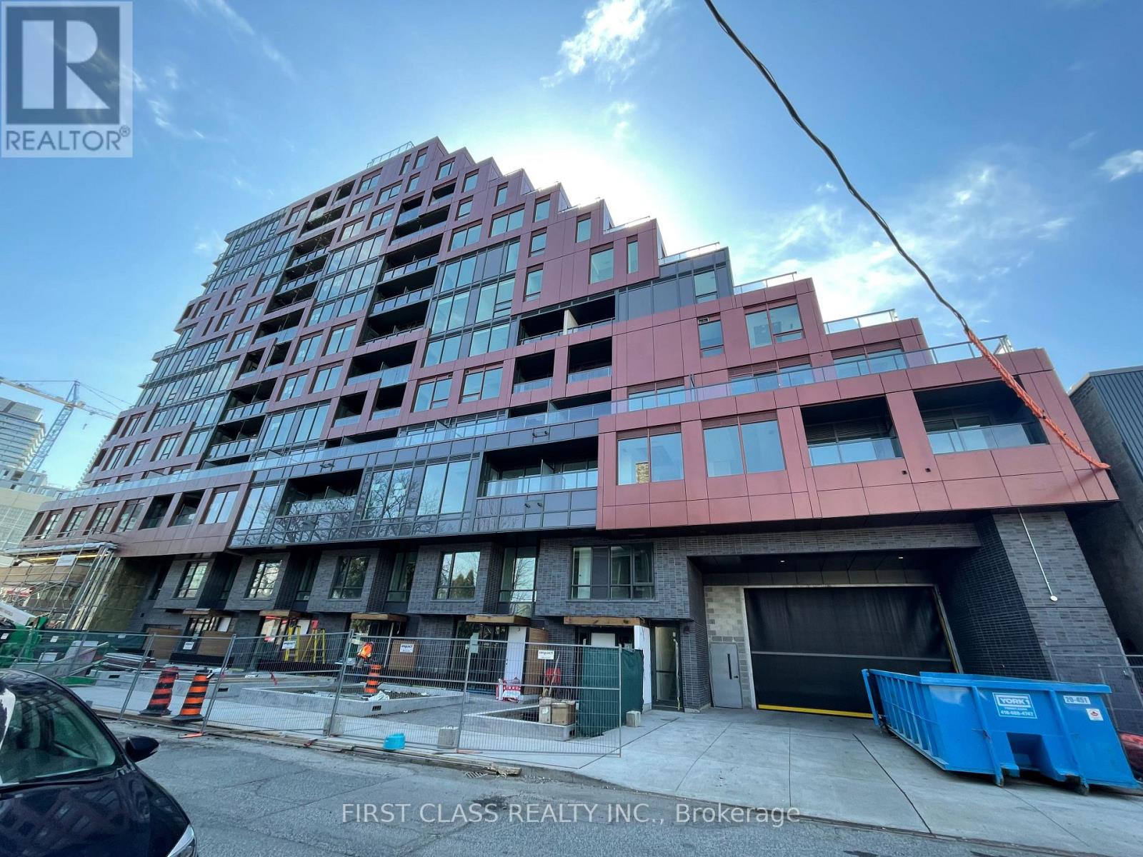 A building under construction with a sign that says "First Class Realty Inc., Brokerage".