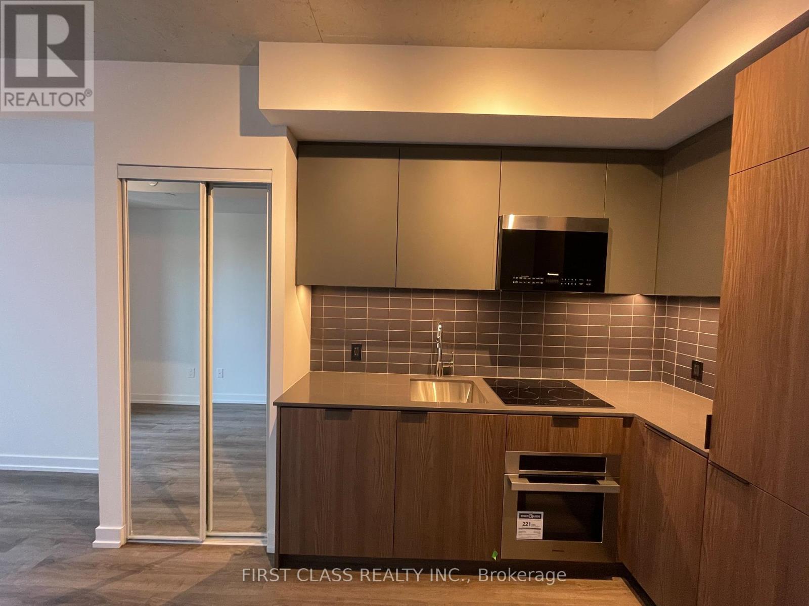 A kitchen with wooden cabinets and a black microwave.