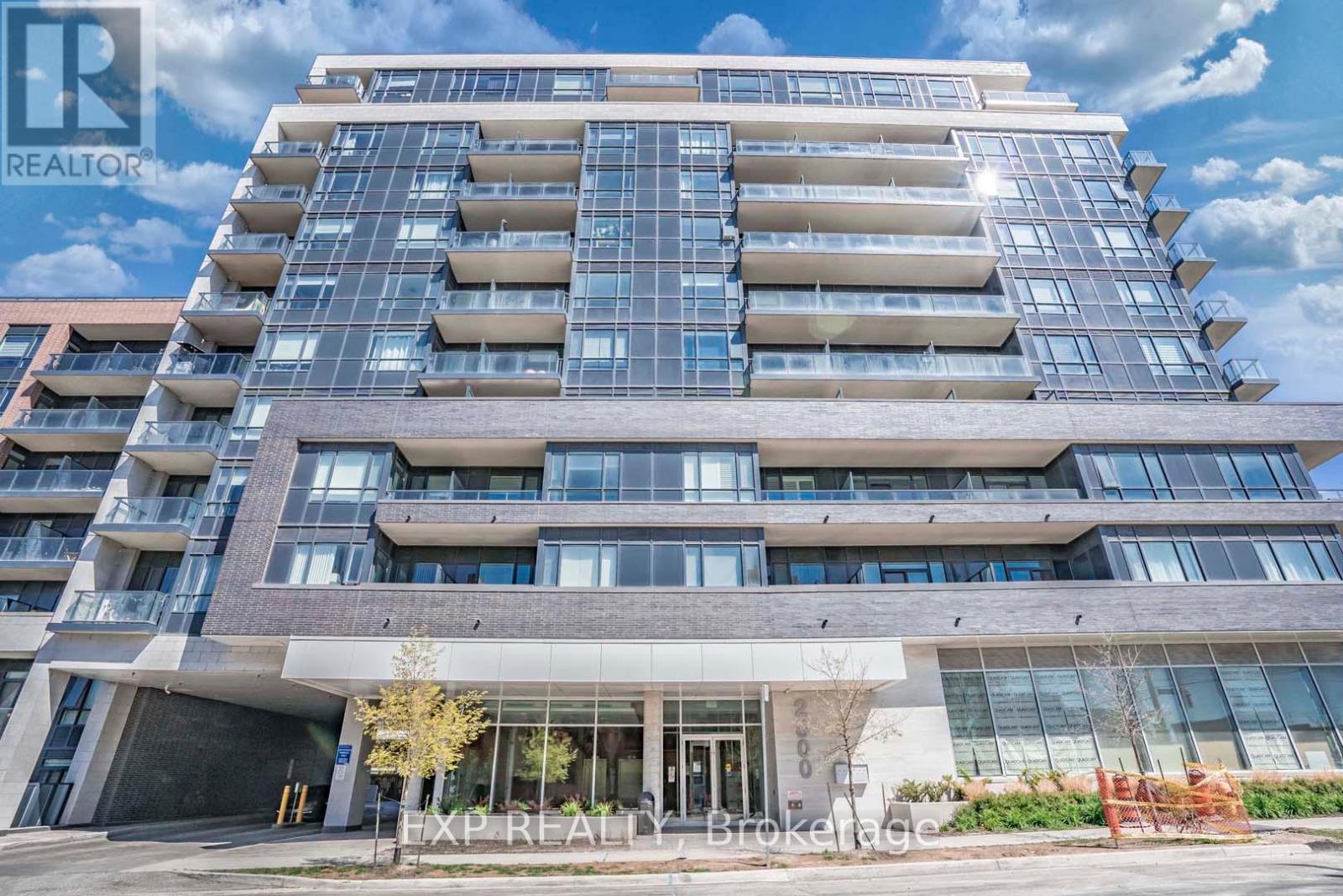 A modern multi-story building with a glass facade and balconies.