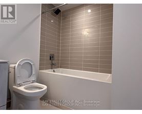 A white toilet sits next to a bathtub in a bathroom.