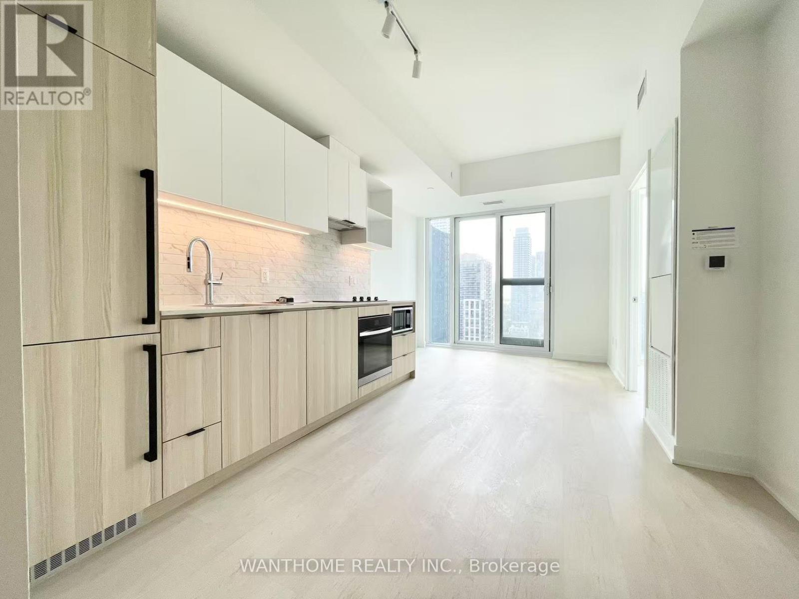 A modern kitchen with wooden cabinets and a large window.