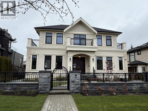 A large, two-story house with a black gate and a brick walkway leading to the entrance.