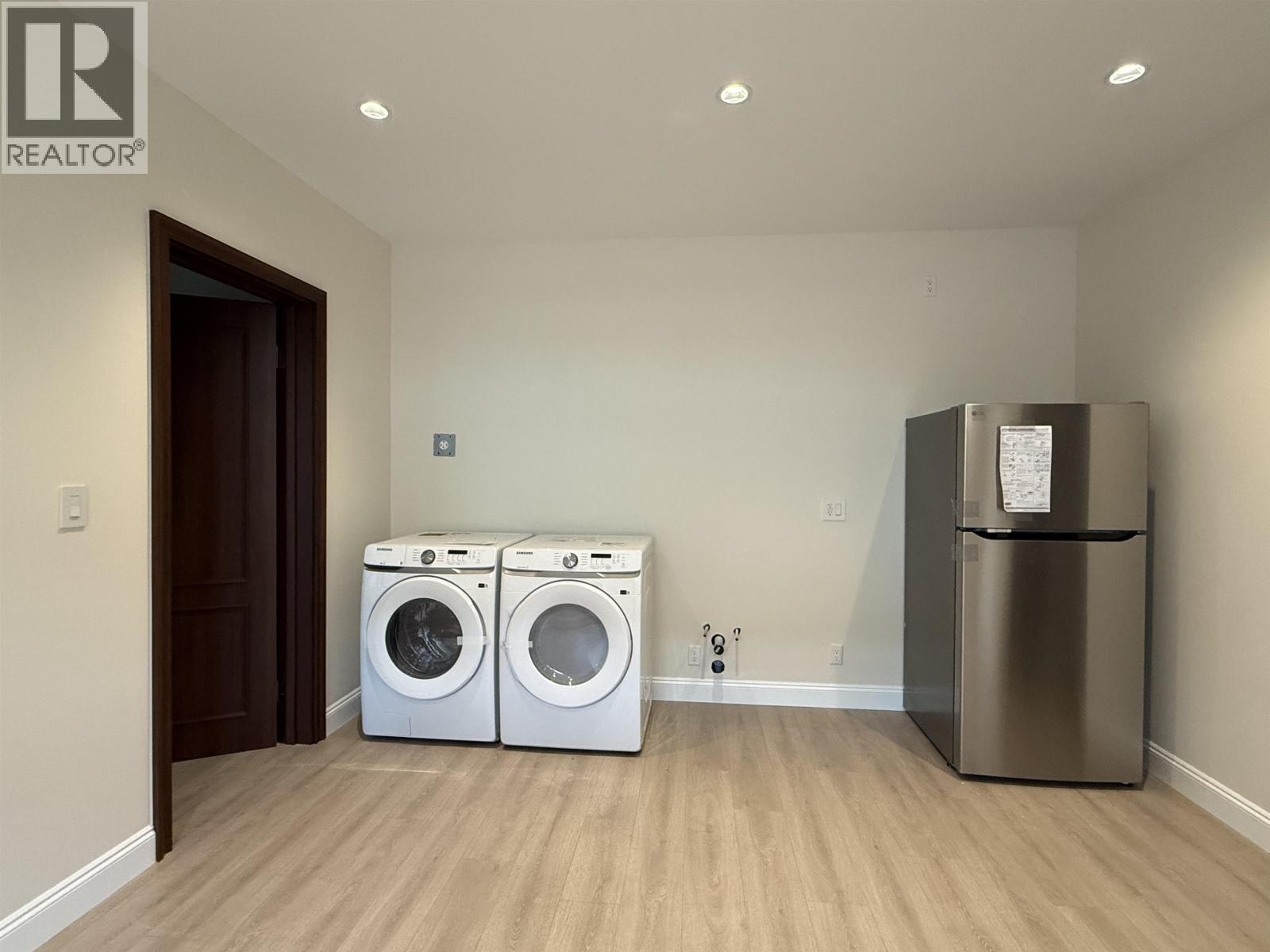 A laundry room with a washer and dryer and a refrigerator.
