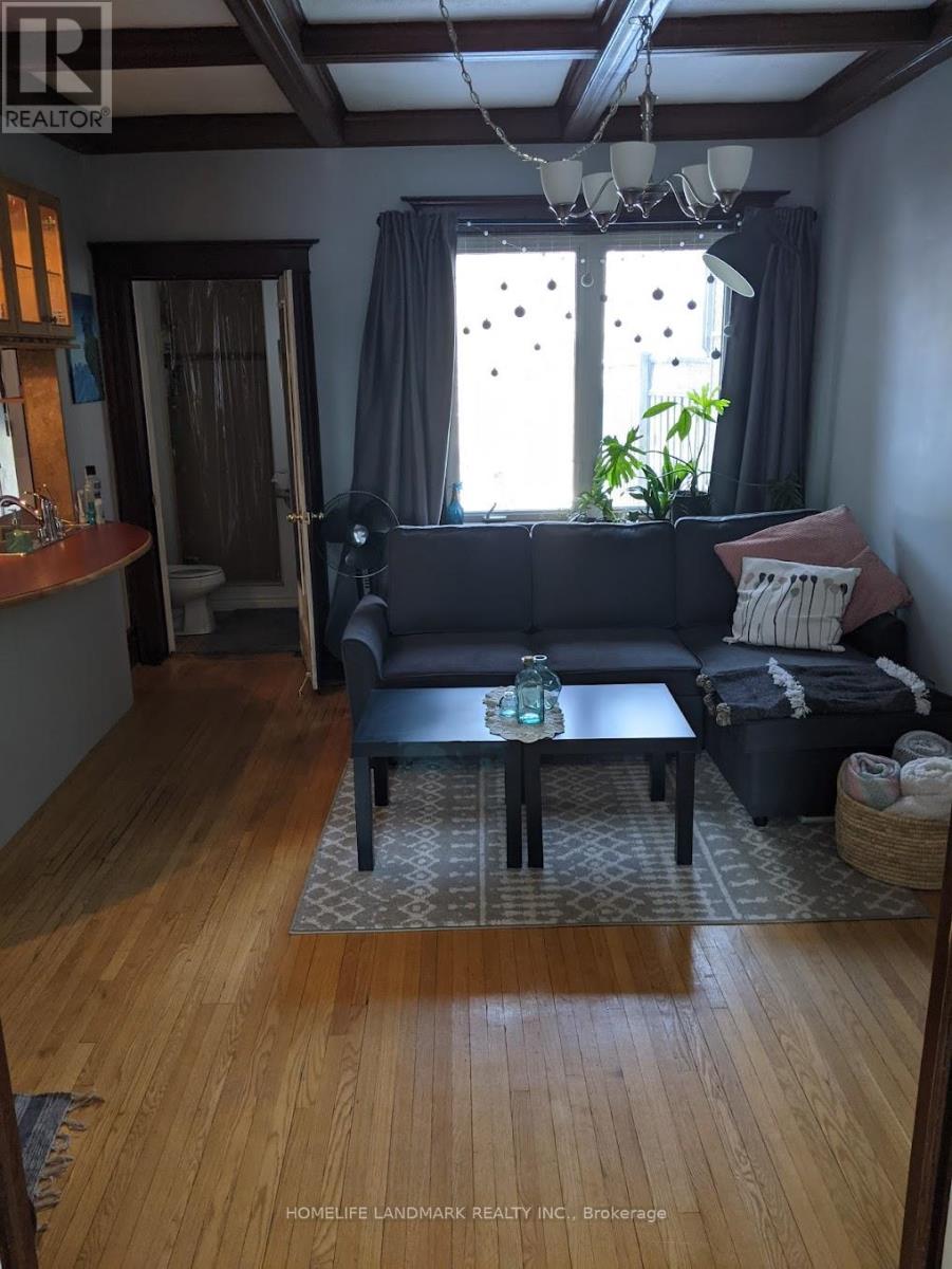 A living room with a black couch and a wooden floor.