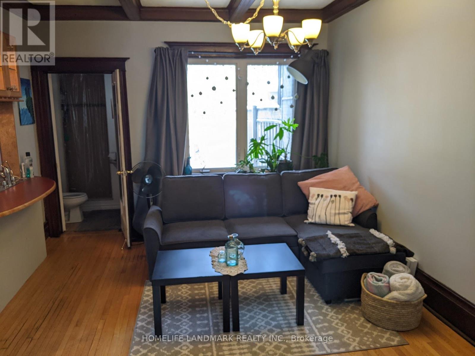 A living room with a grey couch and a wooden floor.