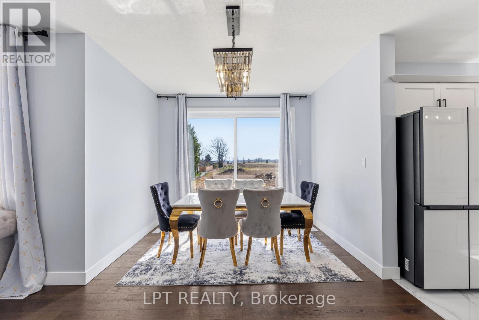 A dining room with a table set for four and a view of the outdoors through the window.