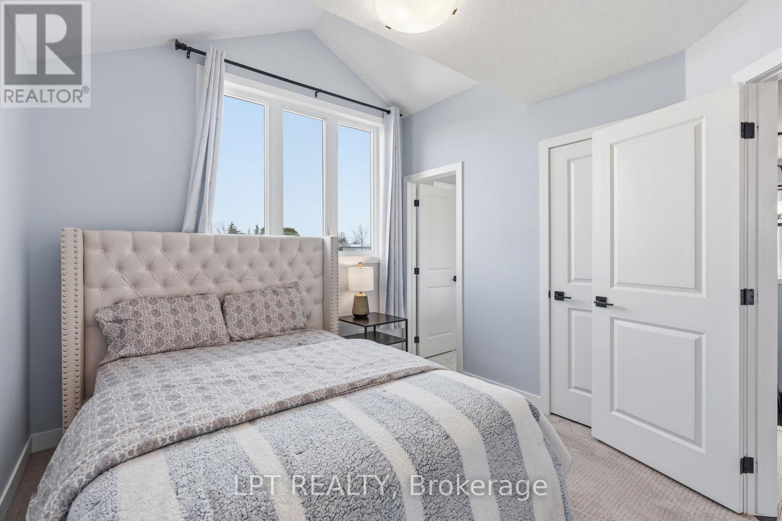 A bedroom with a large bed and a window with curtains.