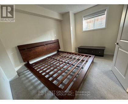 A bedroom with a wooden bed frame and a black dresser.