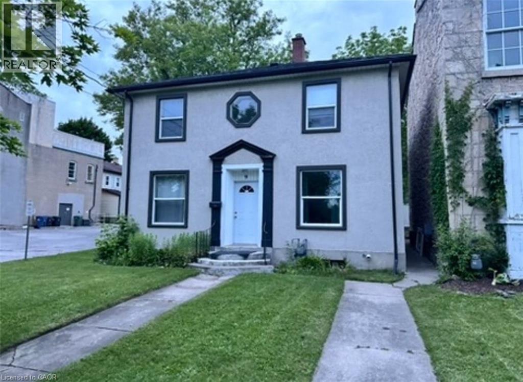A house with a white door and windows is surrounded by a grassy area and a sidewalk.