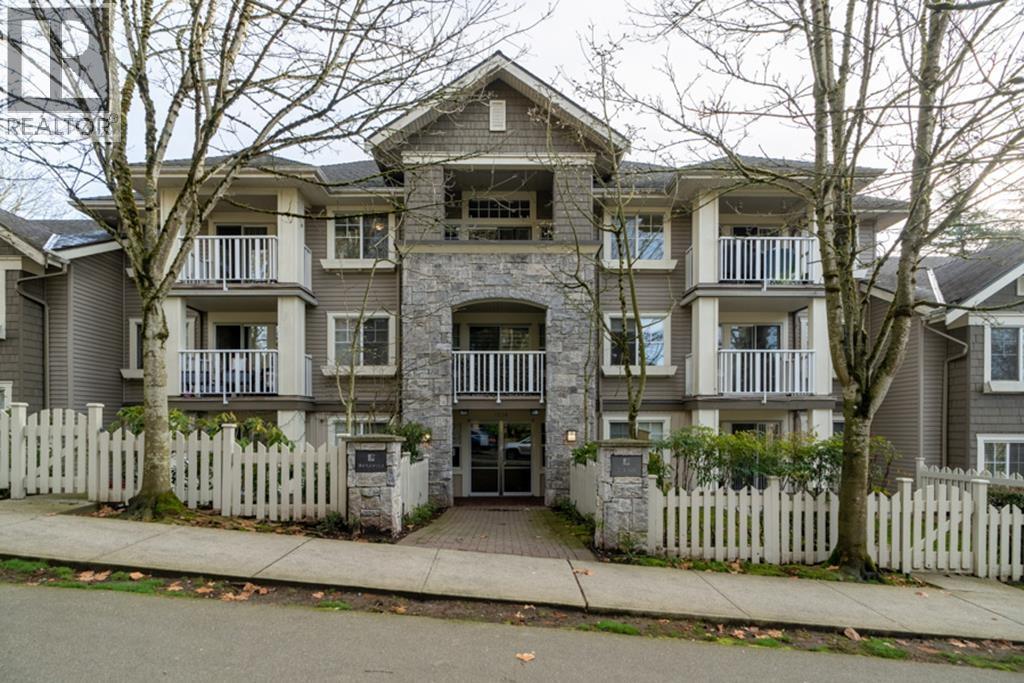 A large apartment building with a white picket fence in front.