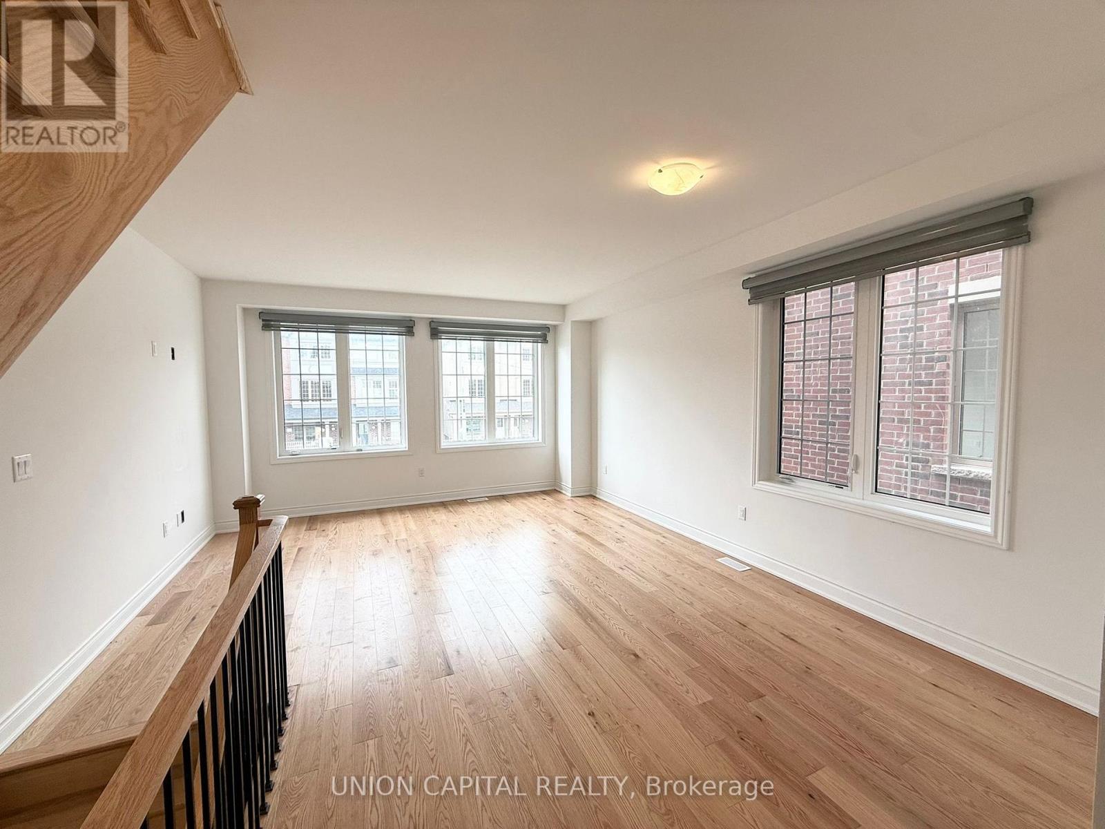 A spacious room with wooden floors and a window with blinds.