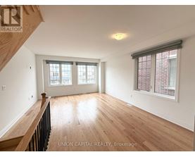 A spacious room with wooden floors and a window with blinds.