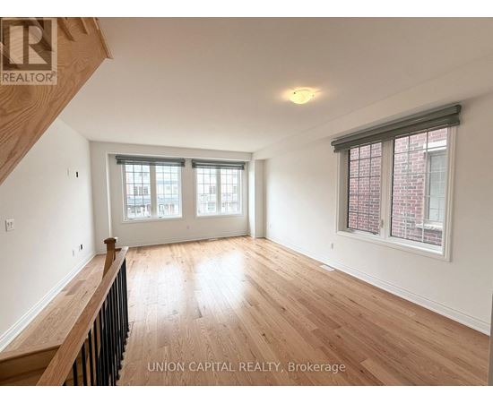 A spacious room with wooden floors and a window with blinds.