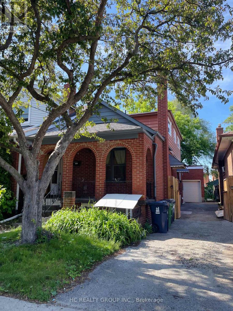 A house with a red brick exterior and a tree in front.