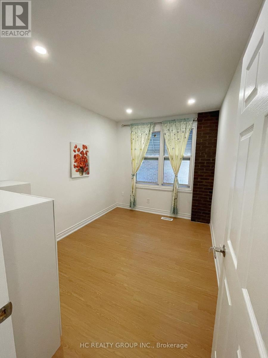 A room with wooden flooring and a window with curtains.