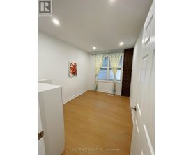 A room with wooden flooring and a window with curtains.