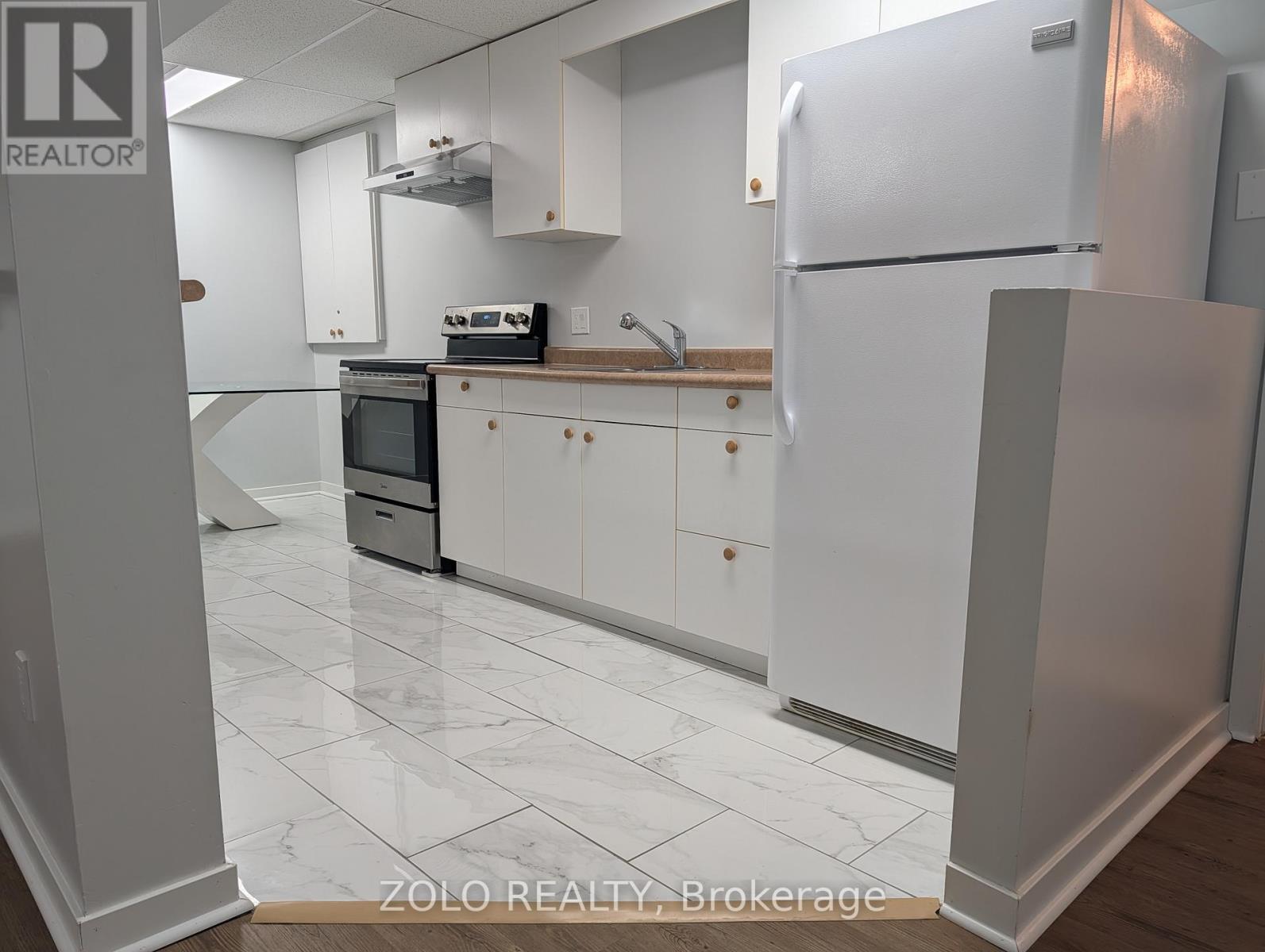 A kitchen with white cabinets and a white fridge.