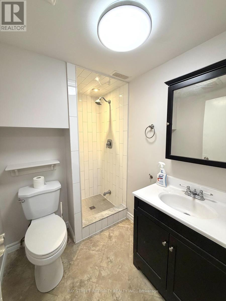 A white toilet is in a bathroom with a black cabinet.
