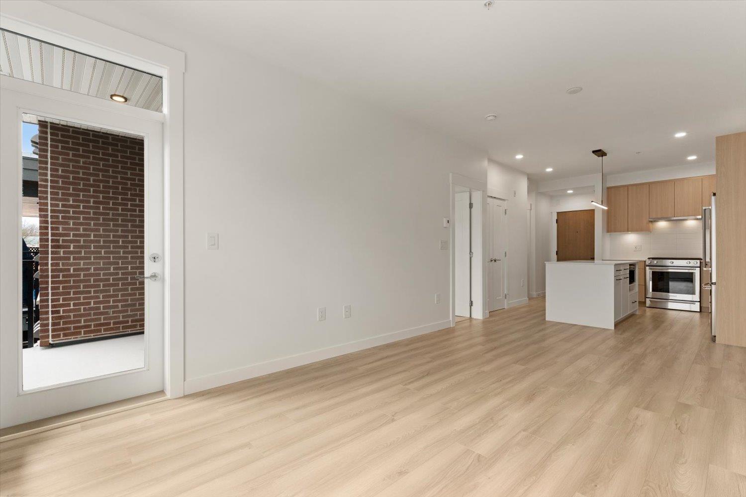 A spacious room with wooden flooring and white walls.