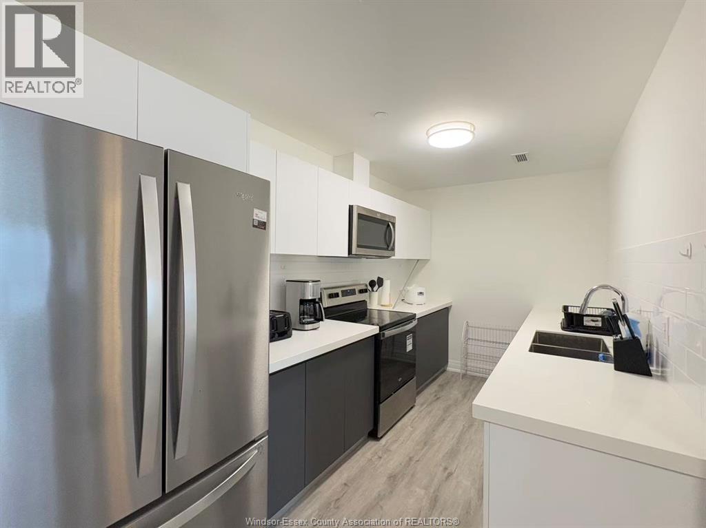 A modern kitchen with a stainless steel refrigerator and a microwave above the stove.