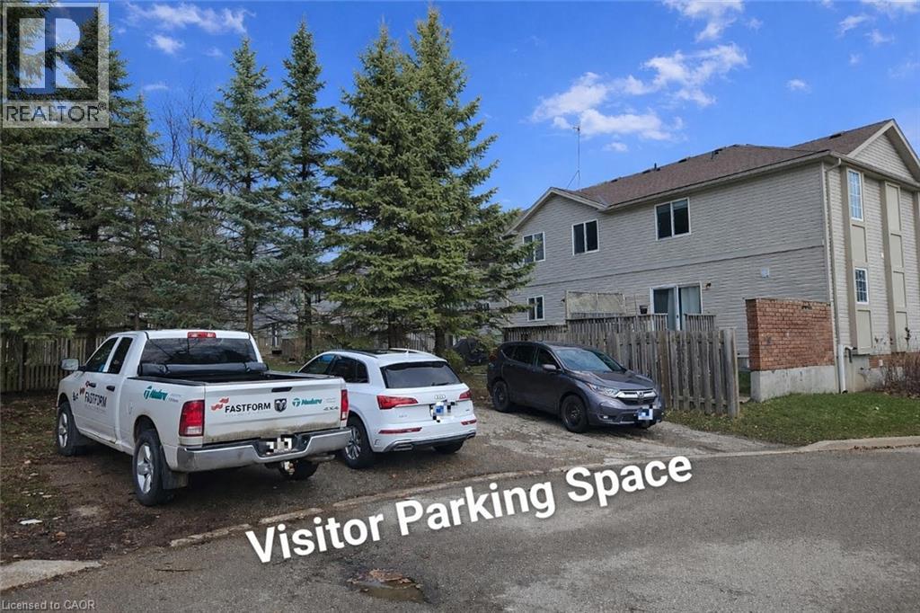 A white pickup truck is parked in front of a house with the words "Visitor Parking Space" written on the image.
